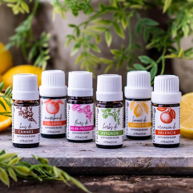 Pranarom Certified Organic Bois de Cannes, Pompelmo di Calabria, Fleurs de Aix-En-Provence, Herbs de Avignon, Limone di Sorrento, Arancia di Valencia Diffusion Blend bottles with green plant background.
