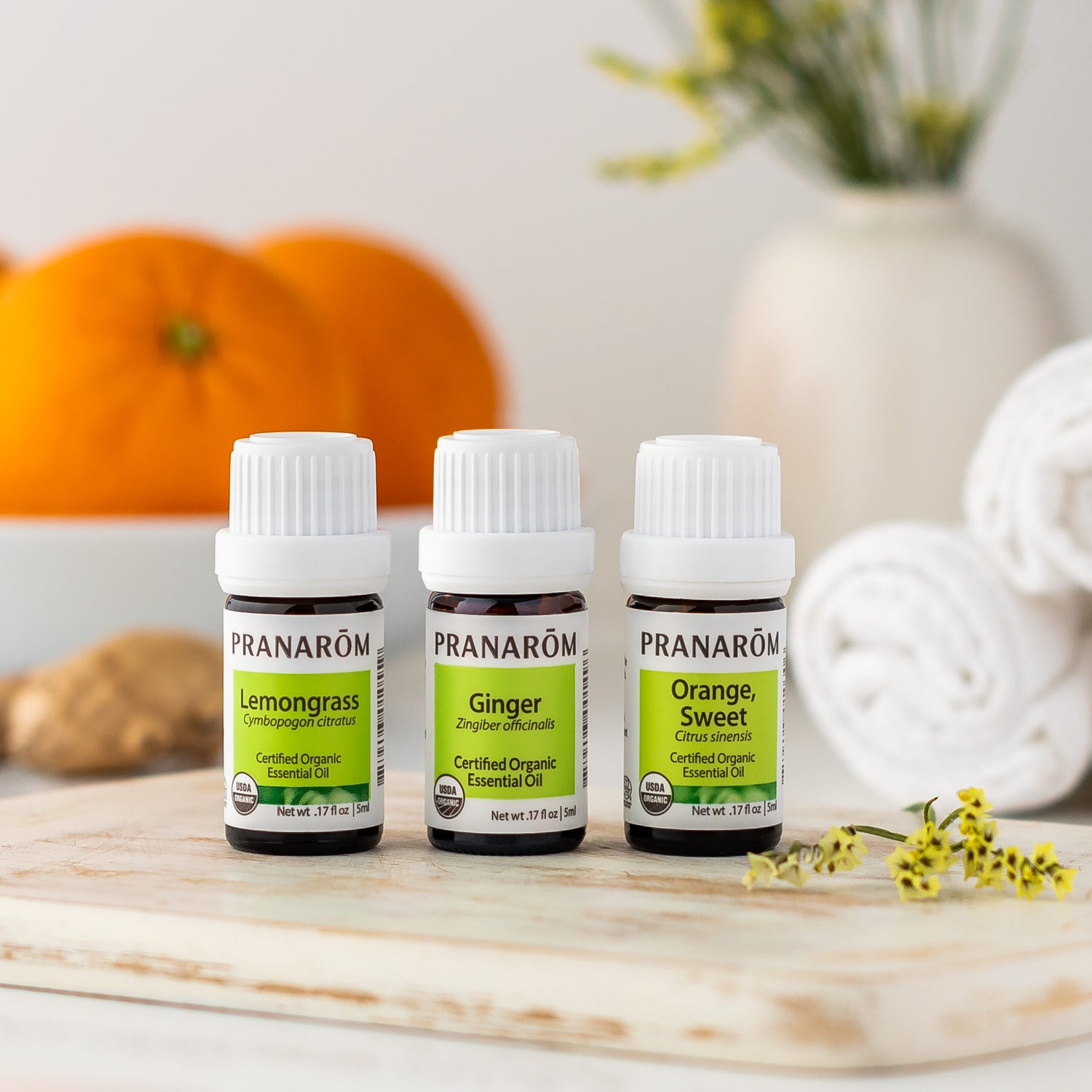Pranarom Certified Organic Lemongrass, Ginger, and Orange, Sweet Essential Oil bottles with oranges and ginger background.