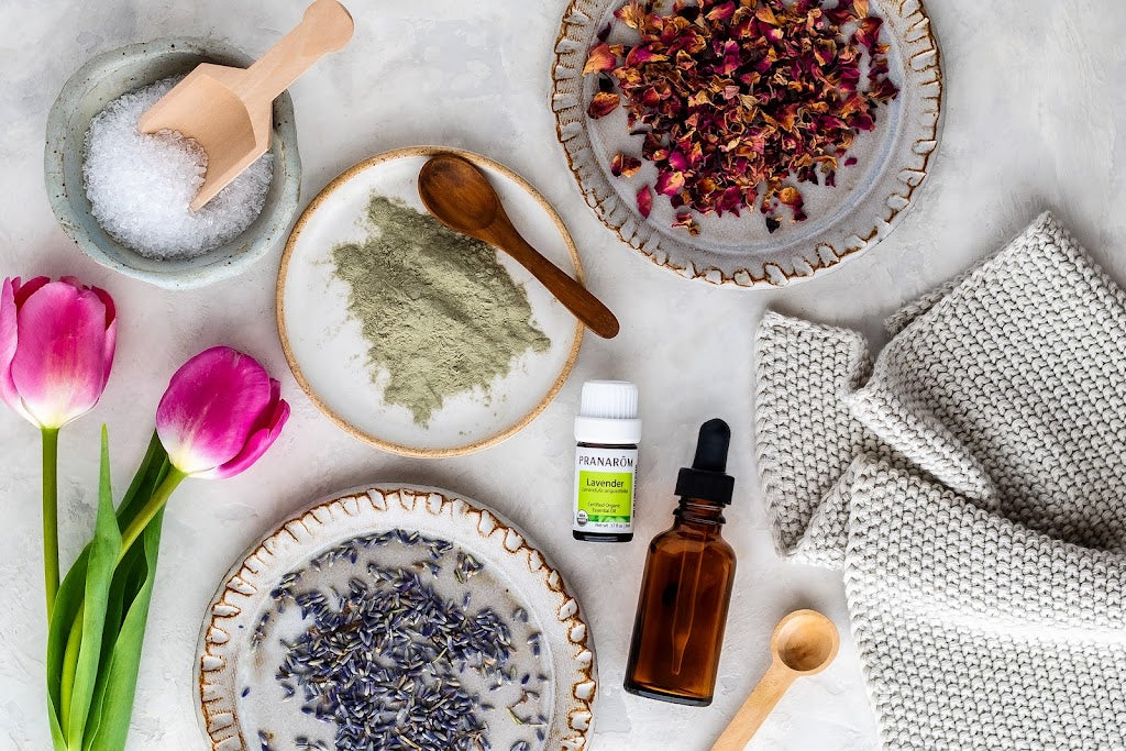 Pranarom Certified Organic Lavender Essential Oil bottle with plates of different plants or powders and towel.