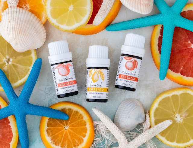 Pranarom Certified Organic Pompelmo di Calabria, Limone di Sorrento, and Arancia di Valencia Diffusion Blend bottles with fruit slices and starfish.