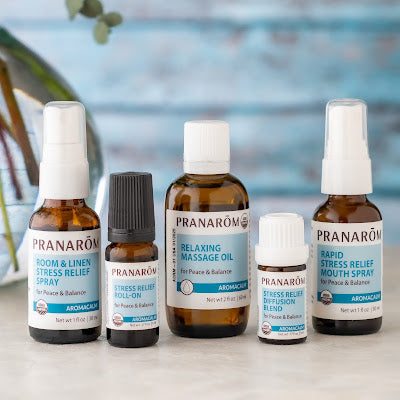 Pranarom Certified Organic Aromacalm Room & Linen Stress Relief Spray, Stress-Relief Roll-On, Relaxing Massage Oil, Stress Relief Diffusion Blend, and Rapid Stress Relief Mouth Spray bottles and blue background.