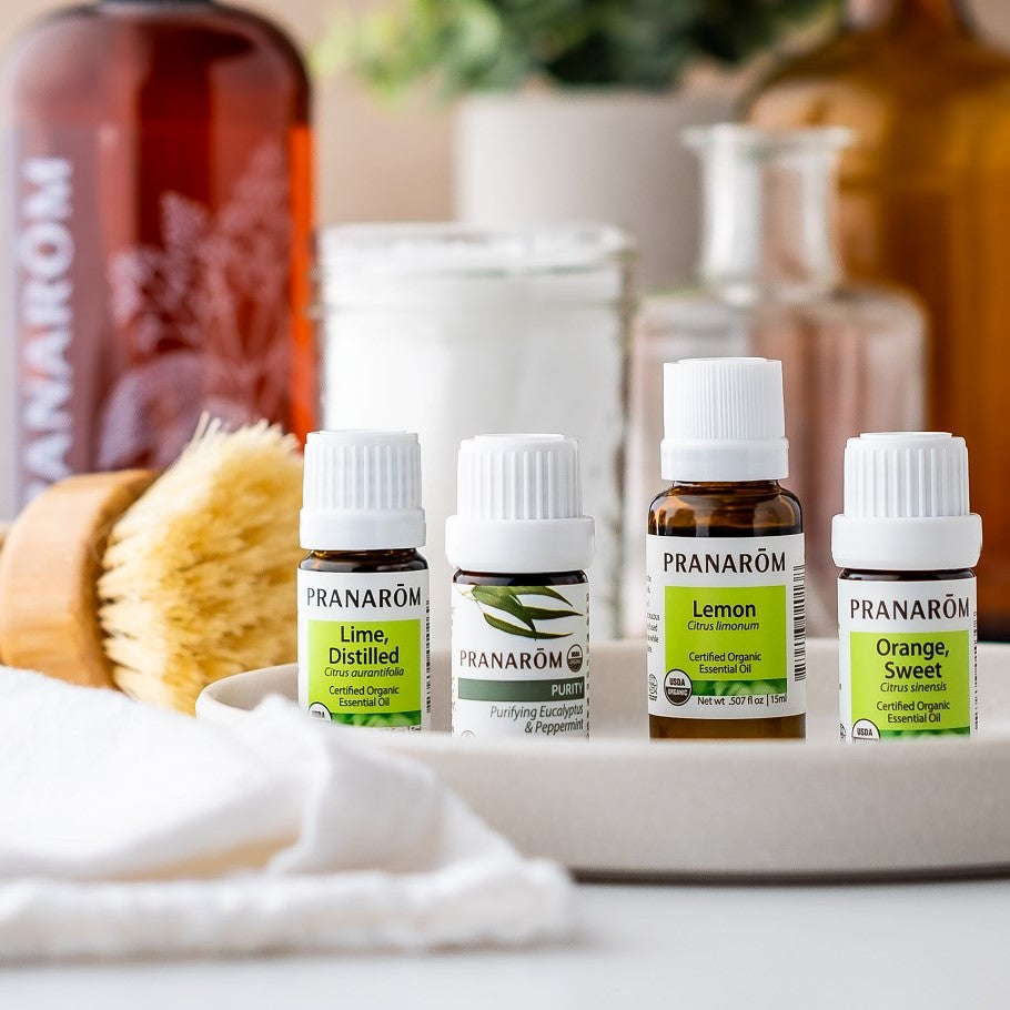 Pranarom Certified Organic Lime, Distilled Essential Oil, Purity Diffusion Blend, Lemon Essential Oil, Orange, Sweet Essential Oil bottles with bottles and towel.